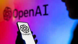 A phone with a floral black and white ChatGPT graphic on it held by a shadowy figure against a rainbow OpenAI background | Jaap Arriens/NurPhoto via ZUMA Press