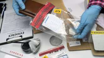 A police officer's gloved hands place a wallet into an evidence bag. | Felipe Caparros Cruz | Dreamstime.com