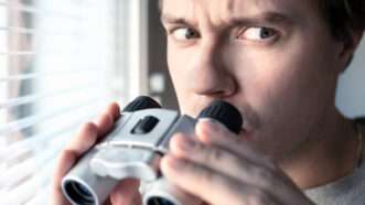 A suspicious man with binoculars, peering out his window. | Tero Vesalainen | Dreamstime.com