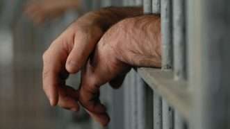 hands hanging out of a prison cell | Willeecole/Dreamstime.com