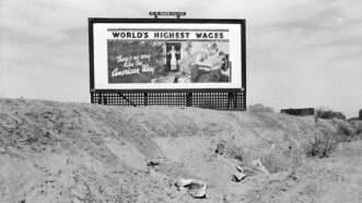 A black and white photo of a billboard reading 'World's highest wages: There is no way like the American way' | Photo: Heritage Image Partnership Ltd./Alamy