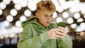 teenage boy looking at a cell phone | Maria Diachenko/Westend61 GmbH/Newscom