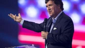 Tucker Carlson gesticulates while speaking on stage at Turning Point USA's December 2022 AmericaFest. | Brian Cahn/ZUMAPRESS/Newscom